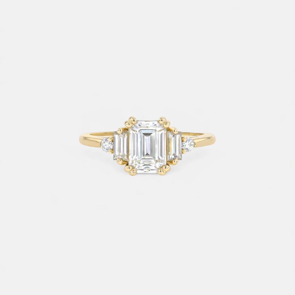 Rings-Product Details - Features an 7 x 5mm emerald cut Supernova Moissanite as the centre stone and baguette and round on the sides- Moissanite is a laboratory created gemstone that is very durable making it suitable for an engagement ring and everyday wear. Moissanite is not a lab grown diamond. The ring will come with a card of authenticity stating that it is featuring a Supernova Moissanite.- The ring is 1.80mm wide and thick-ELIISE MAAR JEWELLERY