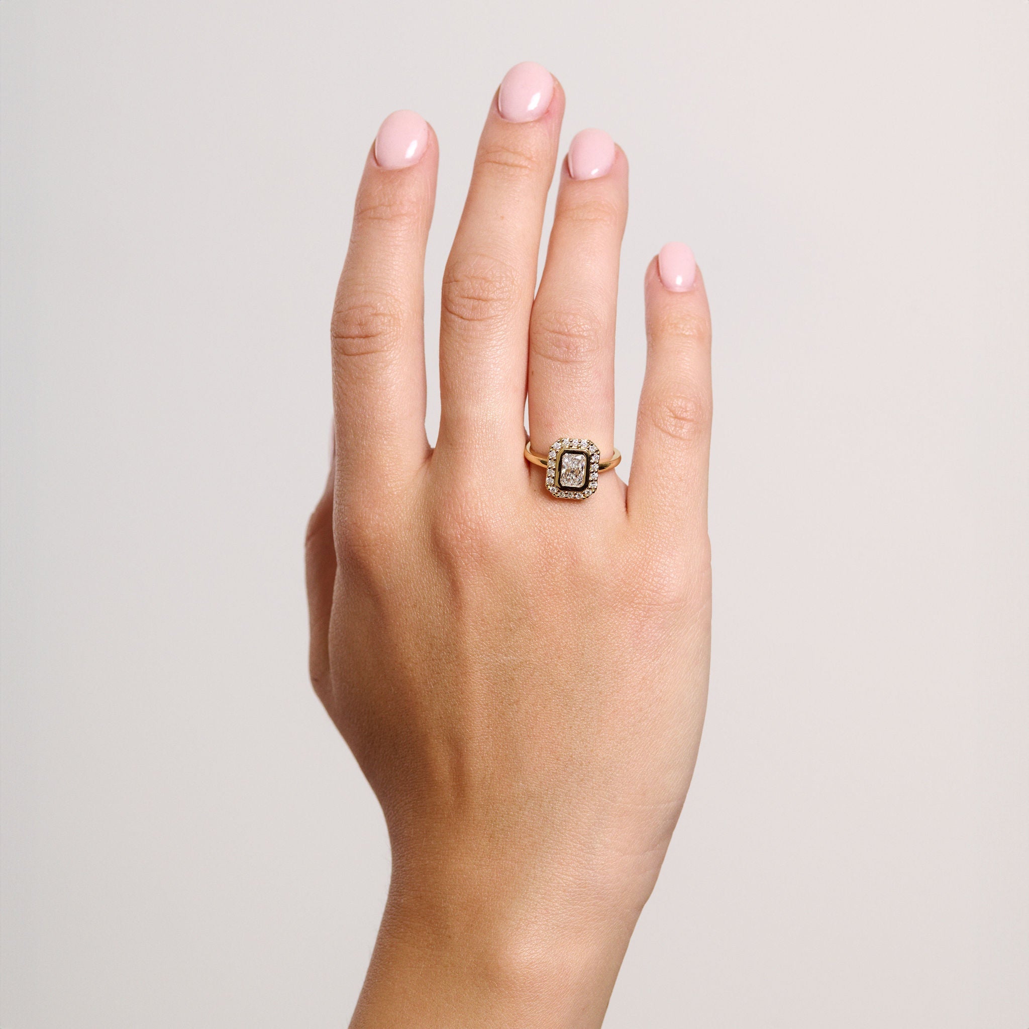 Rings-A contemporary take on an art-deco design. The Holly boasts a stunning bezel set radiant cut centre diamond adorned by a striking halo. This ring uses and enhances the metal in which the stones are set in to create a design that is powerful and elegant.-ELIISE MAAR JEWELLERY