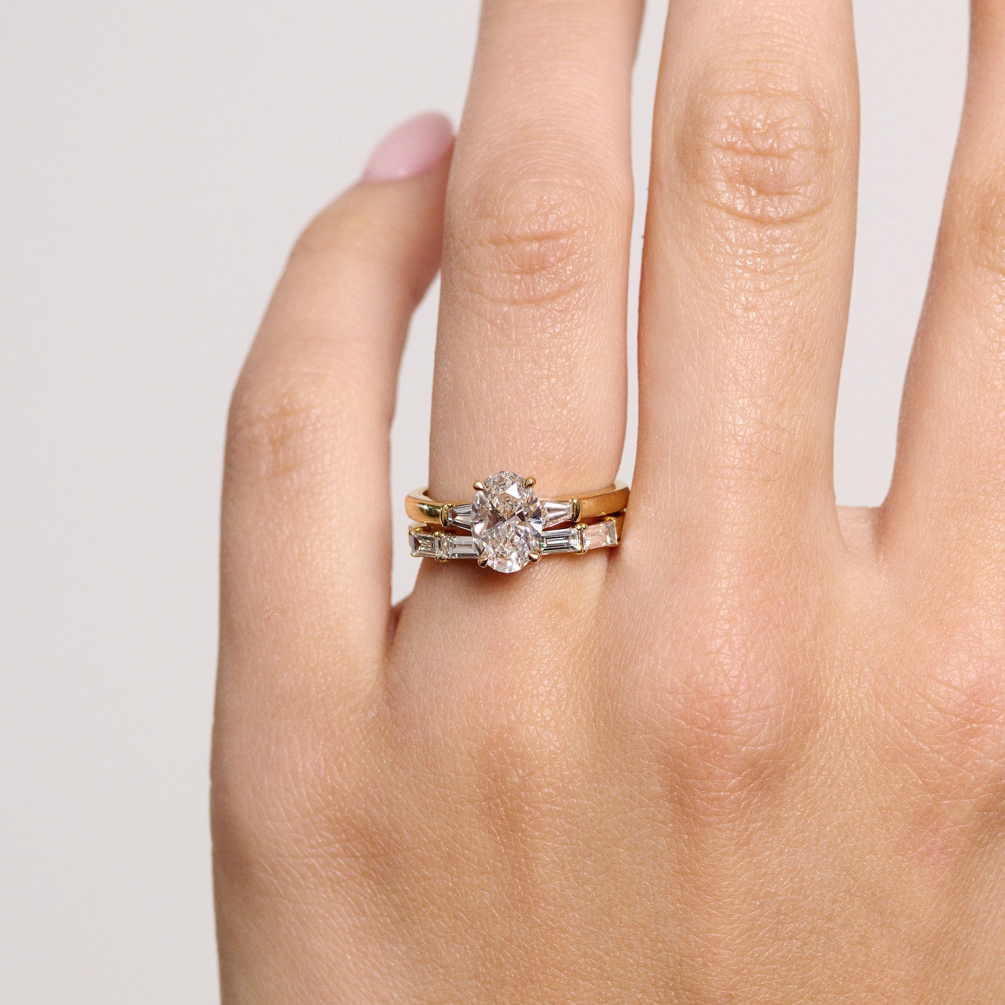 Rings-The Willow is a captivating engagement ring. The side tapered baguette cut stones create a beautiful crescendo to the centre oval cut diamond. The thicker band creates a ring that is structured and impactful. Shown paired with the Petite Nadia.-ELIISE MAAR JEWELLERY