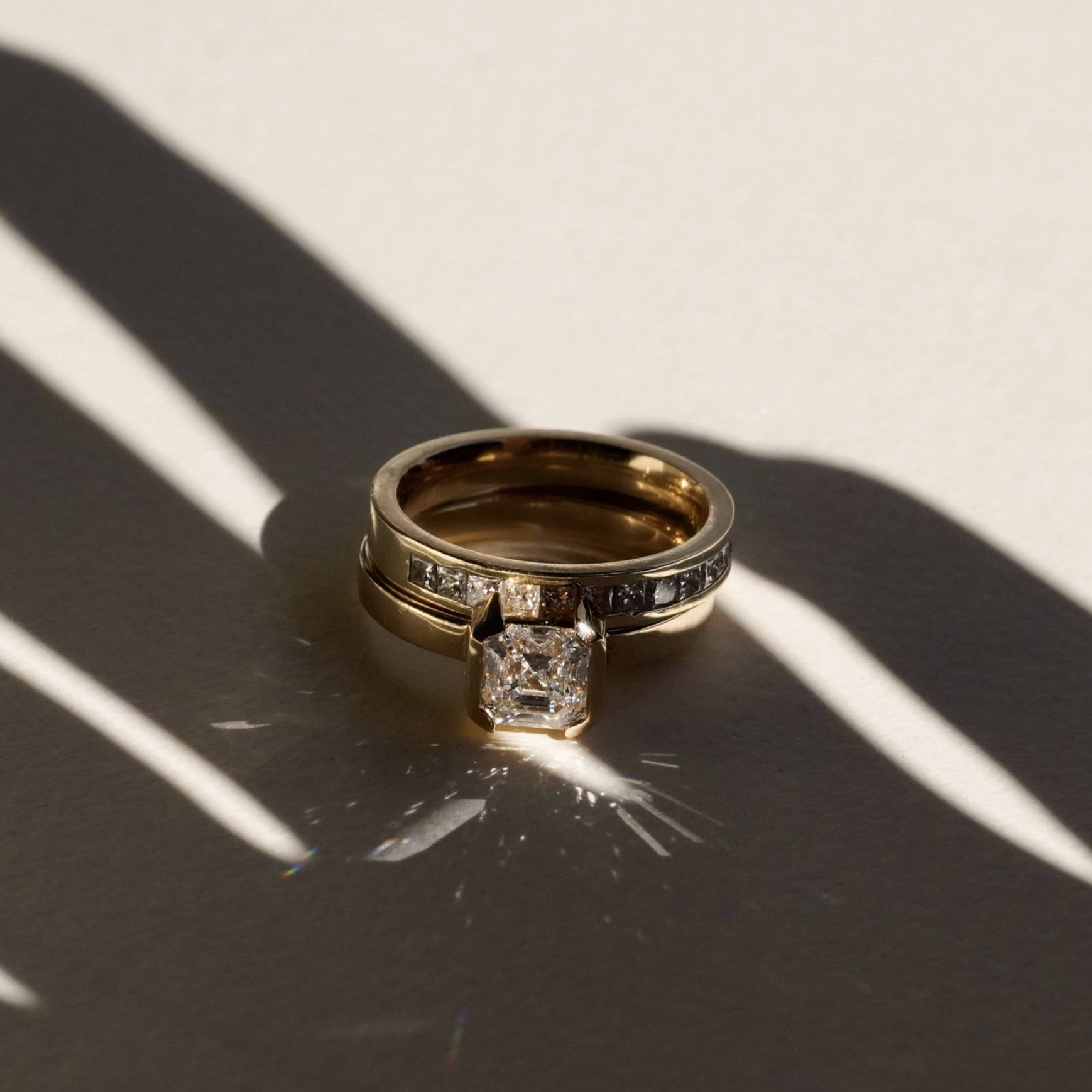 Two gold rings with diamond accents on a textured surface