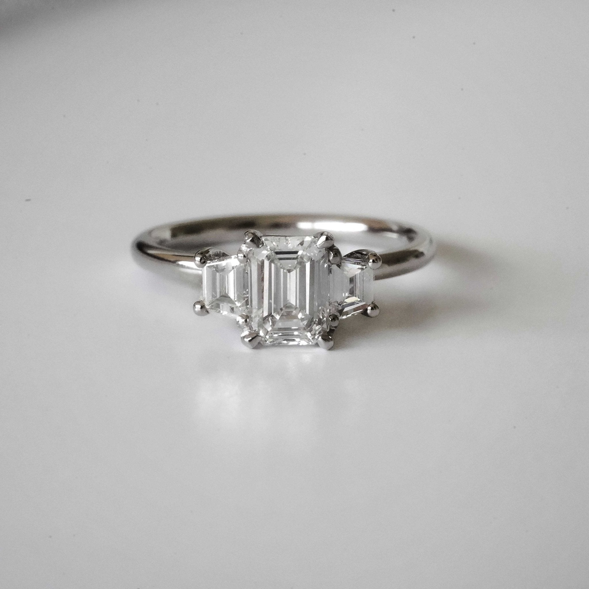 Rings-The Evangeline enhances the intriguing beauty of the emerald-cut diamond with the trapeze cut side stones. The trilogy creates a stunningly geometric shape that is modern and timeless. With the high setting of the stones this engagement ring sits flush with all wedding bands, we recommend pairing with the Bamboo and the Petite Nadia.-ELIISE MAAR JEWELLERY