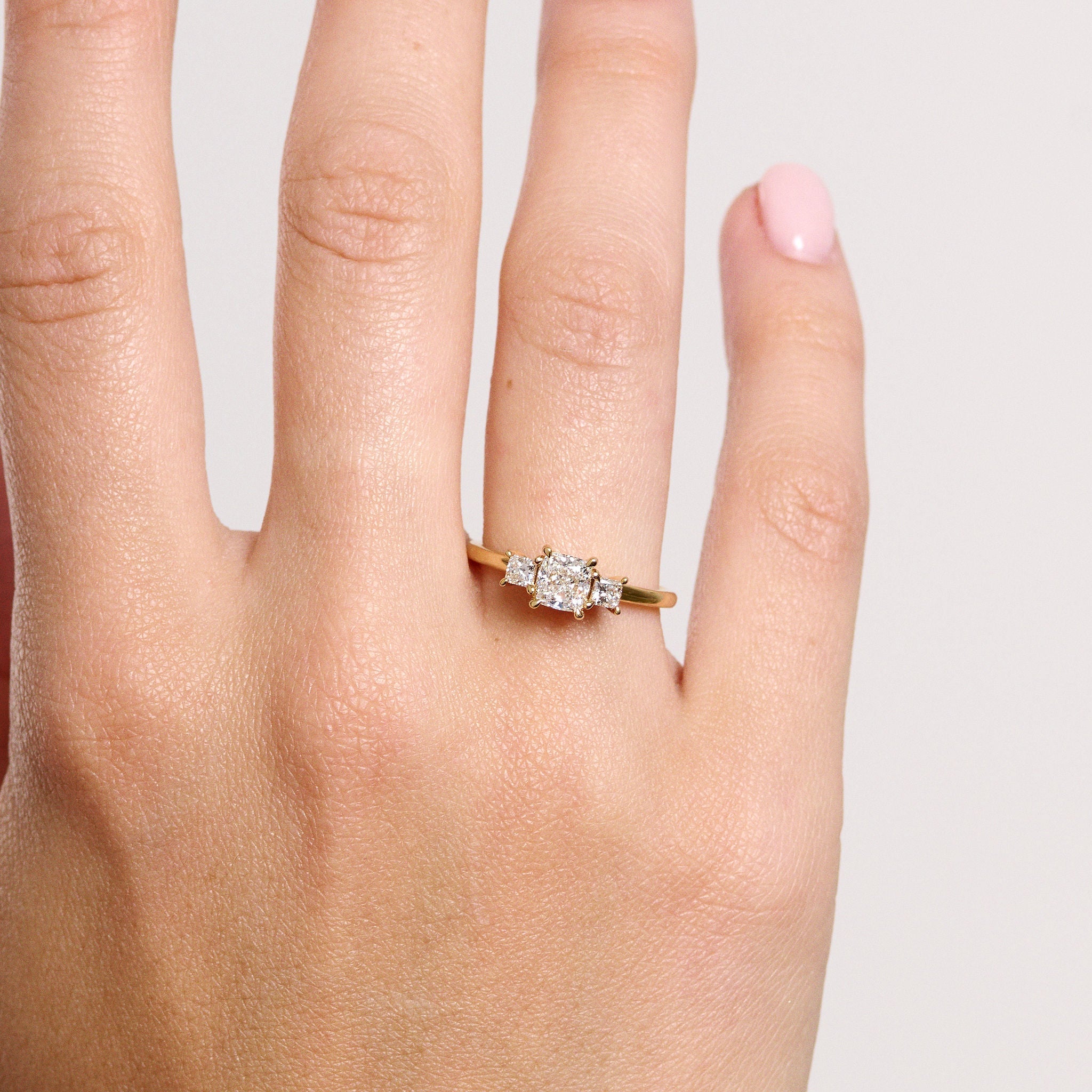 Rings-This elegant trilogy features a cushion cut centre diamond with a brilliant princess cut 0.30ct diamond on either side. VIDEO-ELIISE MAAR JEWELLERY