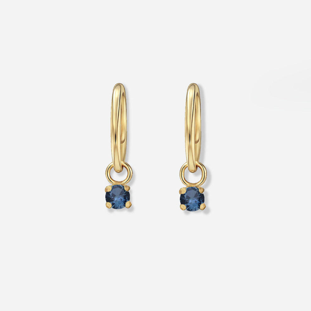 Gold hoop earrings with blue gemstones on a white background