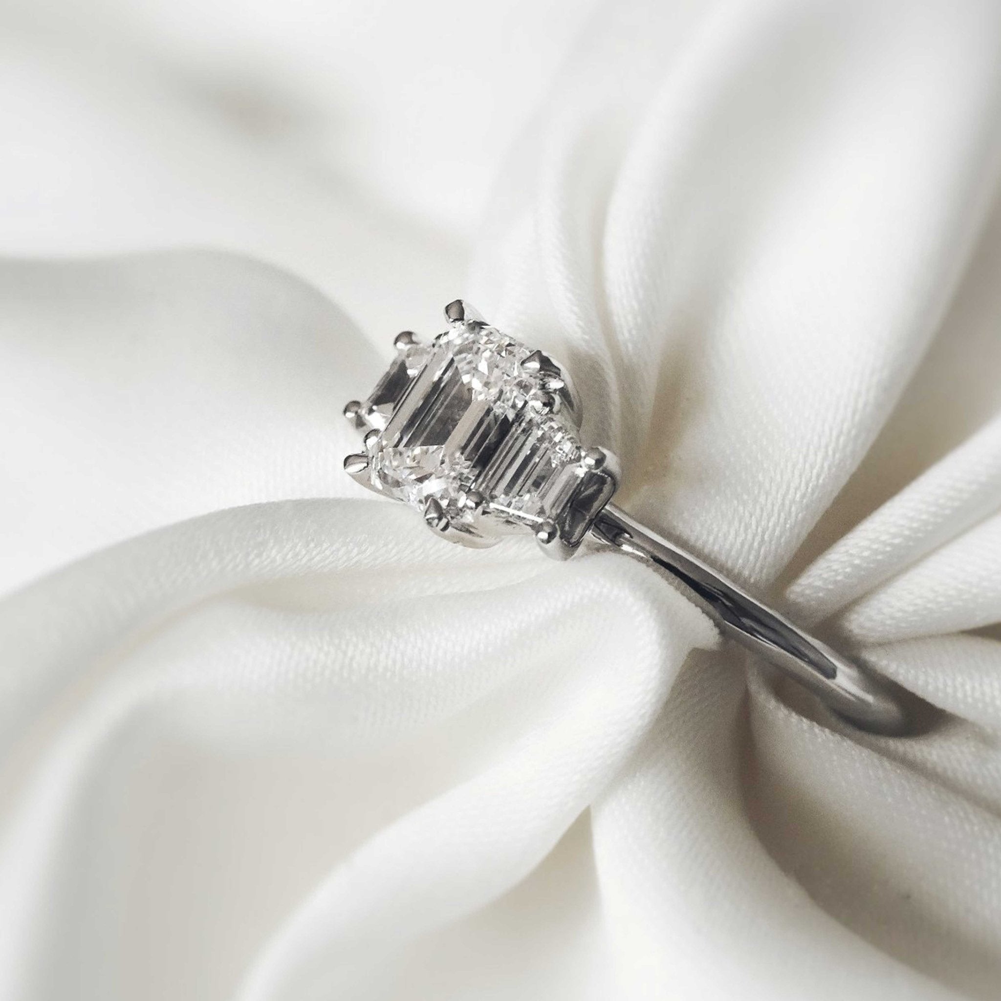 Rings-The Evangeline enhances the intriguing beauty of the emerald-cut diamond with the trapeze cut side stones. The trilogy creates a stunningly geometric shape that is modern and timeless. With the high setting of the stones this engagement ring sits flush with all wedding bands, we recommend pairing with the Bamboo and the Petite Nadia.-ELIISE MAAR JEWELLERY