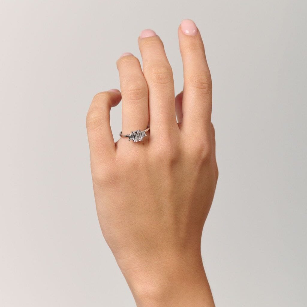 Rings-The Evangeline enhances the intriguing beauty of the emerald-cut diamond with the trapeze cut side stones. The trilogy creates a stunningly geometric shape that is modern and timeless. With the high setting of the stones this engagement ring sits flush with all wedding bands, we recommend pairing with the Bamboo and the Petite Nadia.-ELIISE MAAR JEWELLERY