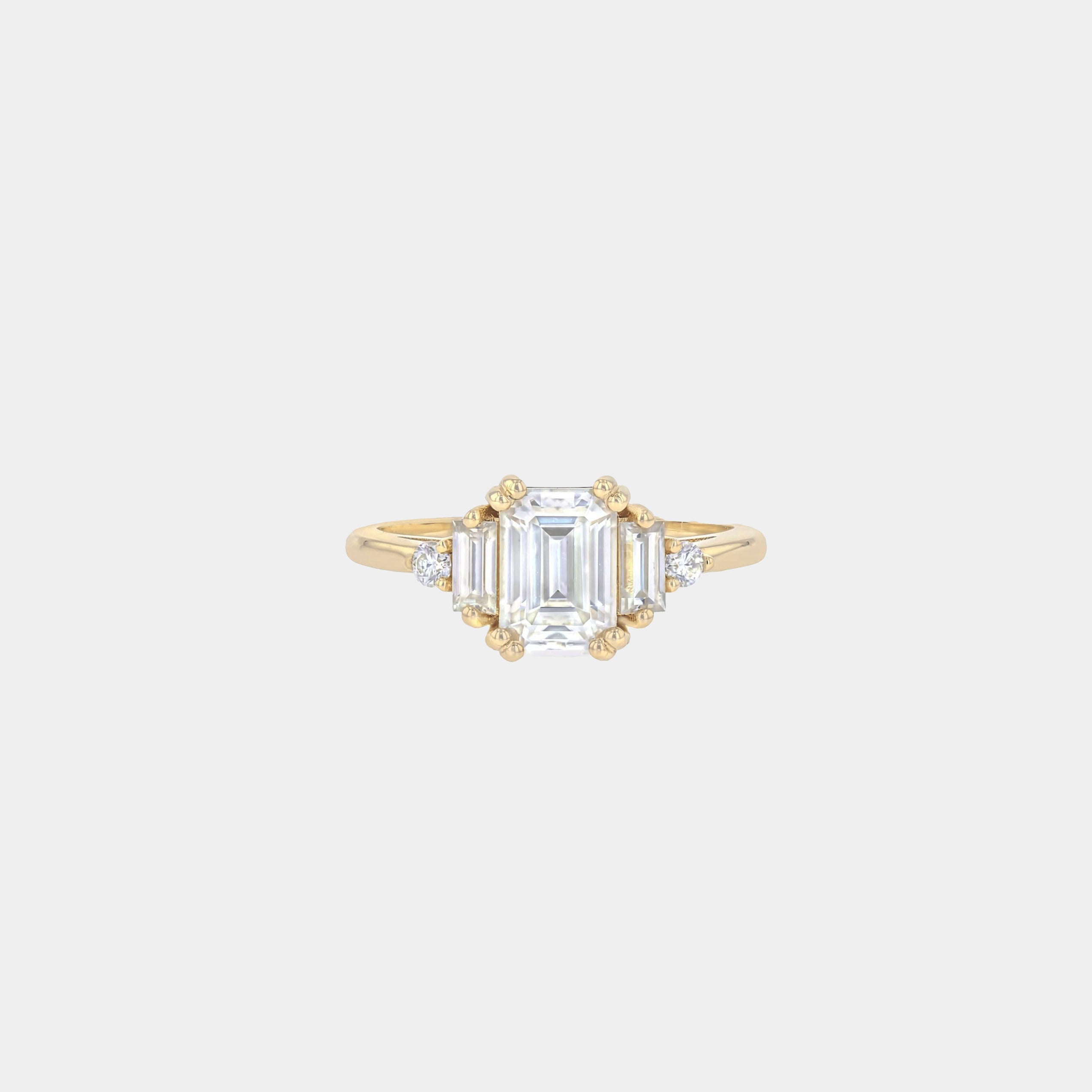Rings-Product Details - Features an 7 x 5mm emerald cut Supernova Moissanite as the centre stone and baguette and round on the sides- Moissanite is a laboratory created gemstone that is very durable making it suitable for an engagement ring and everyday wear. Moissanite is not a lab grown diamond. The ring will come with a card of authenticity stating that it is featuring a Supernova Moissanite.- The ring is 1.80mm wide and thick-ELIISE MAAR JEWELLERY