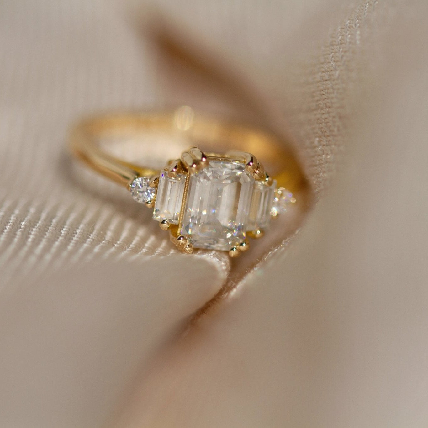 Rings-Product Details - Features an 7 x 5mm emerald cut Supernova Moissanite as the centre stone and baguette and round on the sides- Moissanite is a laboratory created gemstone that is very durable making it suitable for an engagement ring and everyday wear. Moissanite is not a lab grown diamond. The ring will come with a card of authenticity stating that it is featuring a Supernova Moissanite.- The ring is 1.80mm wide and thick-ELIISE MAAR JEWELLERY