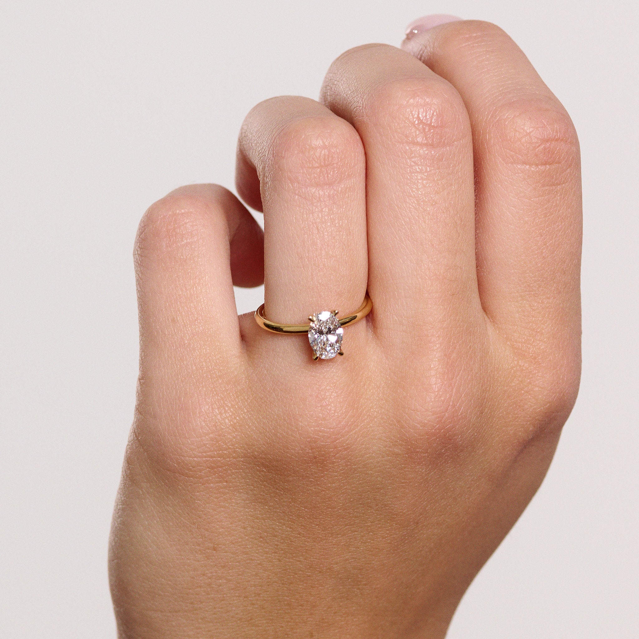 Rings-Drawing inspiration from Grace Kelly, this solitaire ring embodies timeless elegance. Featuring a 4-claw setting and a smoothly rounded band, it offers a subtle frame that highlights the radiant oval diamond at its center. An ideal engagement ring, it complements any wedding band to form a distinctive and personalized set. Shown paired with the 4.0mm Ceremonial Square Band and the Eleanor Luxe Diamond Band.-ELIISE MAAR JEWELLERY