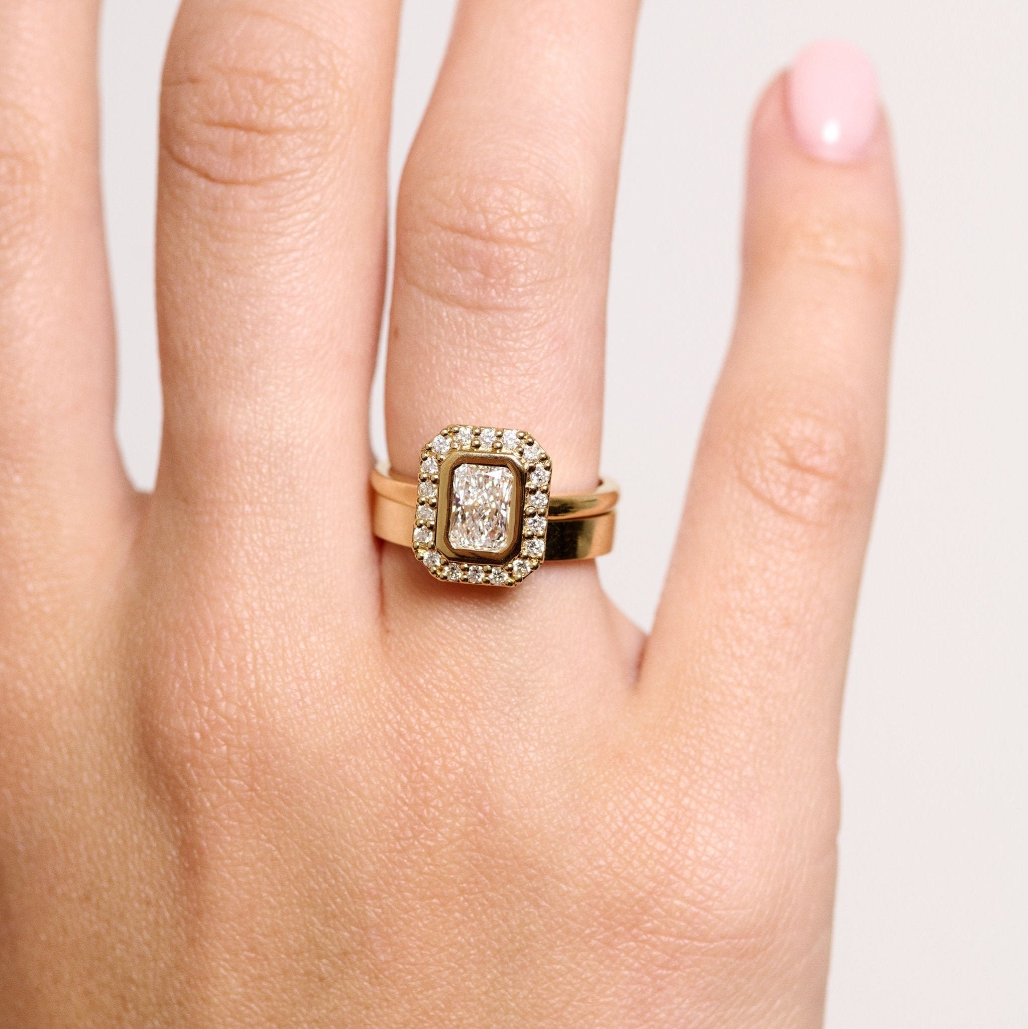 Rings-A contemporary take on an art-deco design. The Holly boasts a stunning bezel set radiant cut centre diamond adorned by a striking halo. This ring uses and enhances the metal in which the stones are set in to create a design that is powerful and elegant.-ELIISE MAAR JEWELLERY