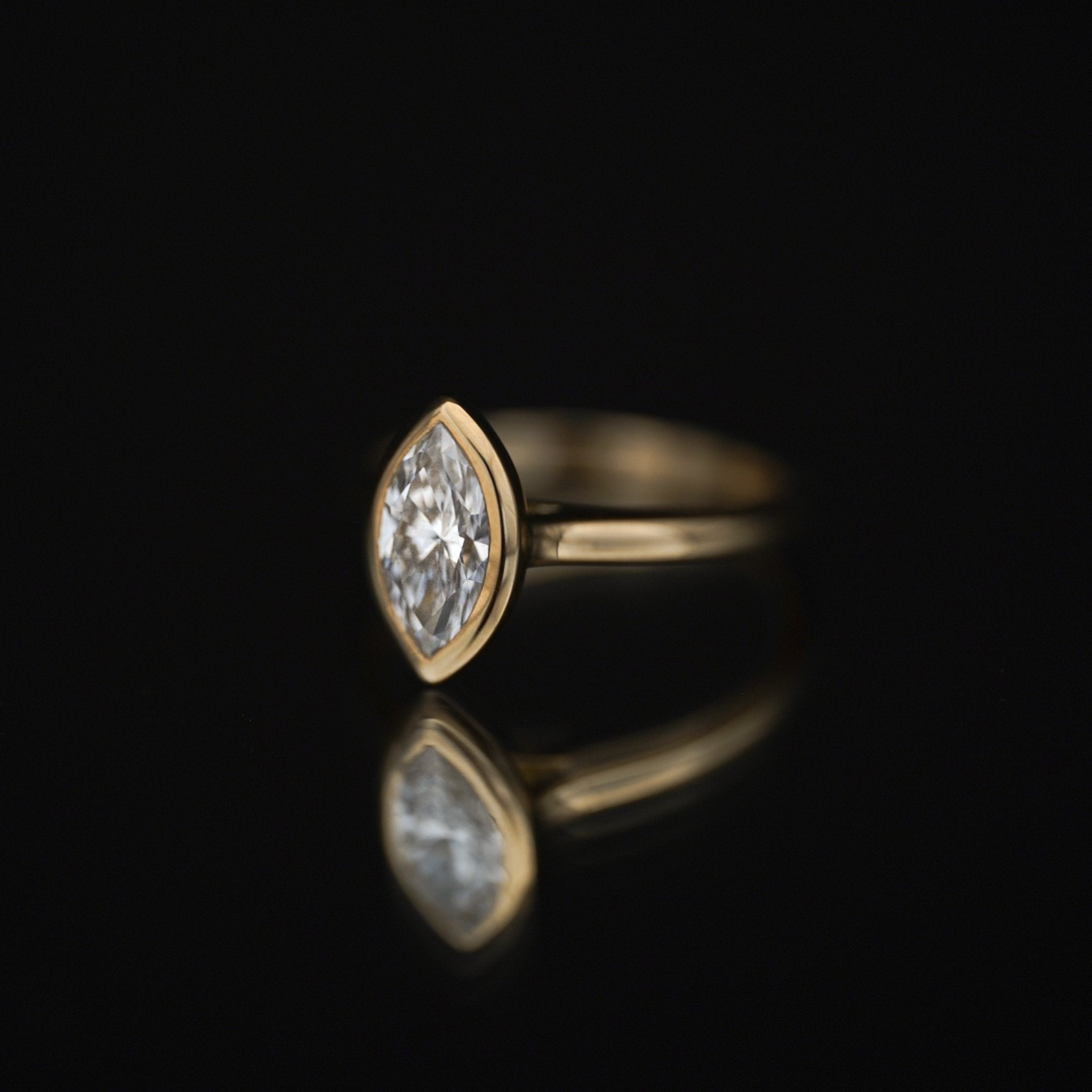Rings-The Selena is a timeless marquise bezel solitaire engagement ring that exudes modern elegance with its sleek and protective bezel setting. Featuring a dazzling marquise-cut diamond, its elongated silhouette enhances brilliance while adding a touch of sophistication. Perfect for those who appreciate minimalist beauty, The Selena is a captivating symbol of love and style.-ELIISE MAAR JEWELLERY