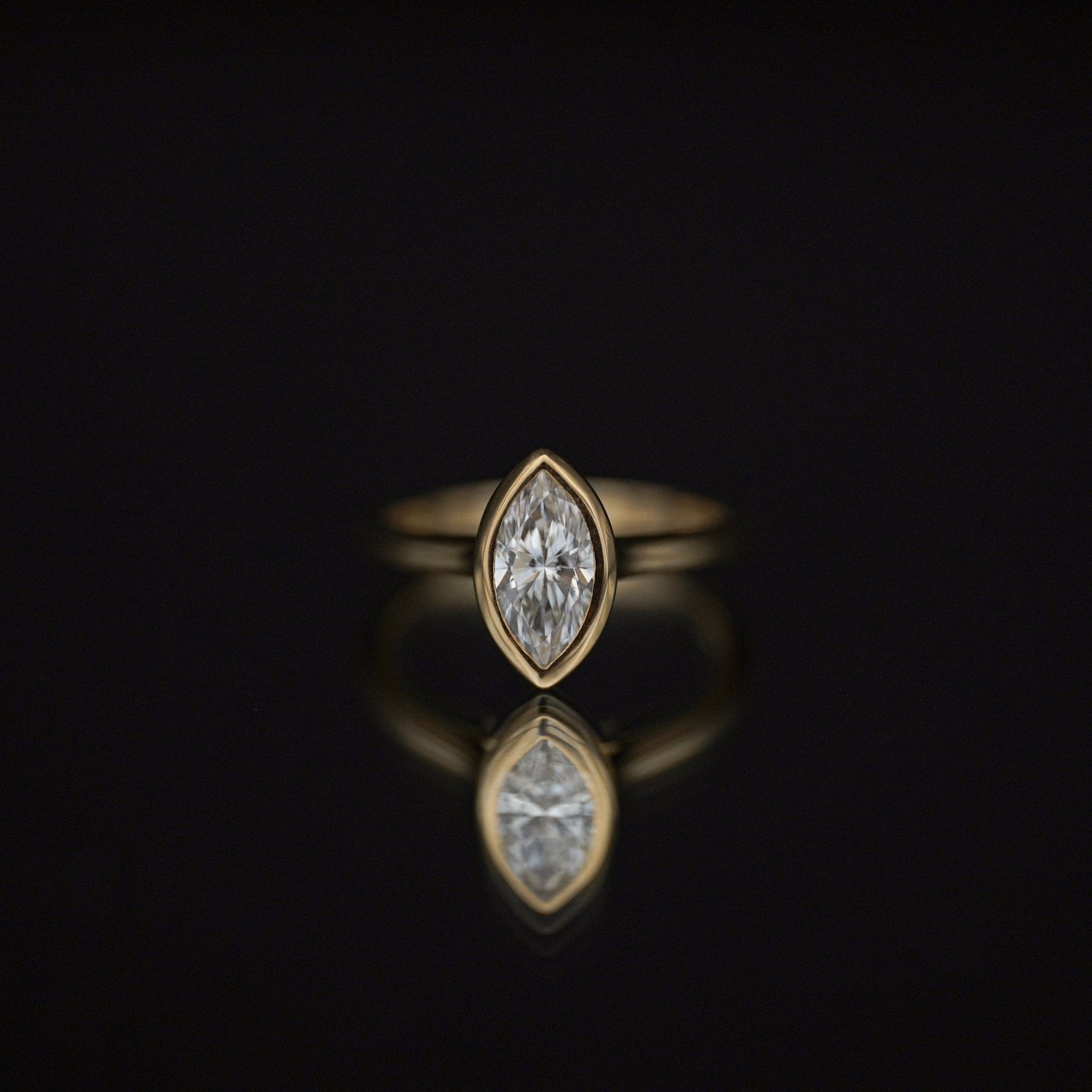 Rings-The Selena is a timeless marquise bezel solitaire engagement ring that exudes modern elegance with its sleek and protective bezel setting. Featuring a dazzling marquise-cut diamond, its elongated silhouette enhances brilliance while adding a touch of sophistication. Perfect for those who appreciate minimalist beauty, The Selena is a captivating symbol of love and style.-ELIISE MAAR JEWELLERY
