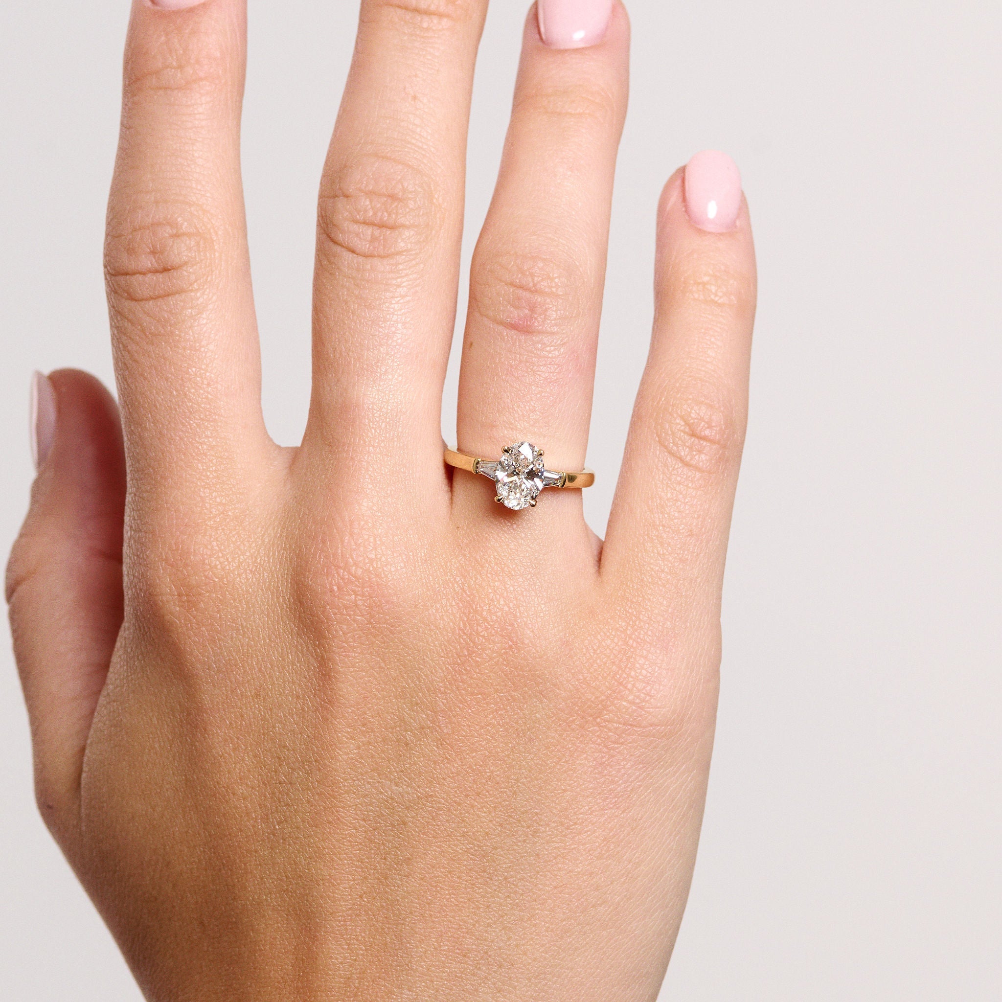 Rings-The Willow is a captivating engagement ring. The side tapered baguette cut stones create a beautiful crescendo to the centre oval cut diamond. The thicker band creates a ring that is structured and impactful. Shown paired with the Petite Nadia.-ELIISE MAAR JEWELLERY