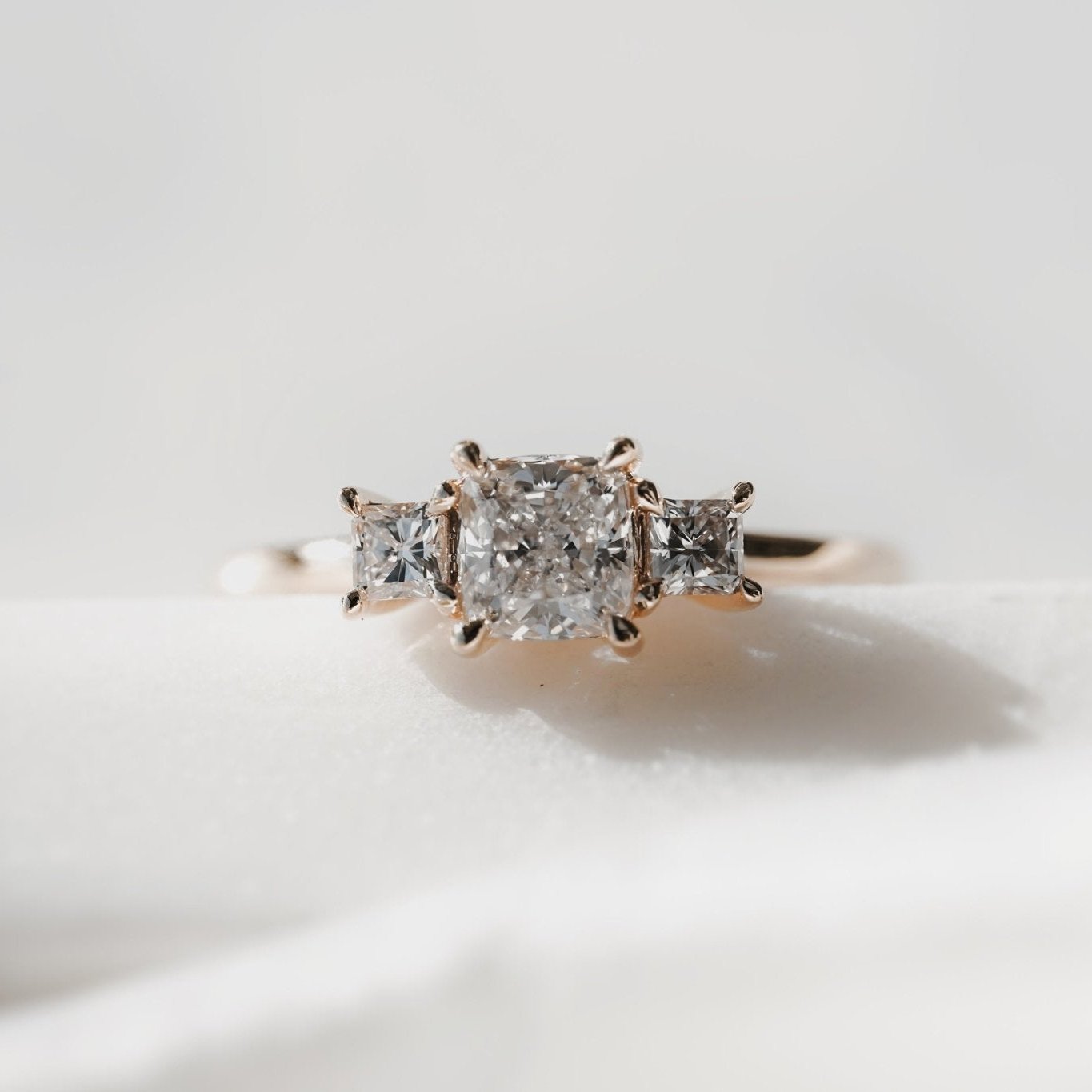 Rings-This elegant trilogy features a cushion cut centre diamond with a brilliant princess cut 0.30ct diamond on either side. VIDEO-ELIISE MAAR JEWELLERY