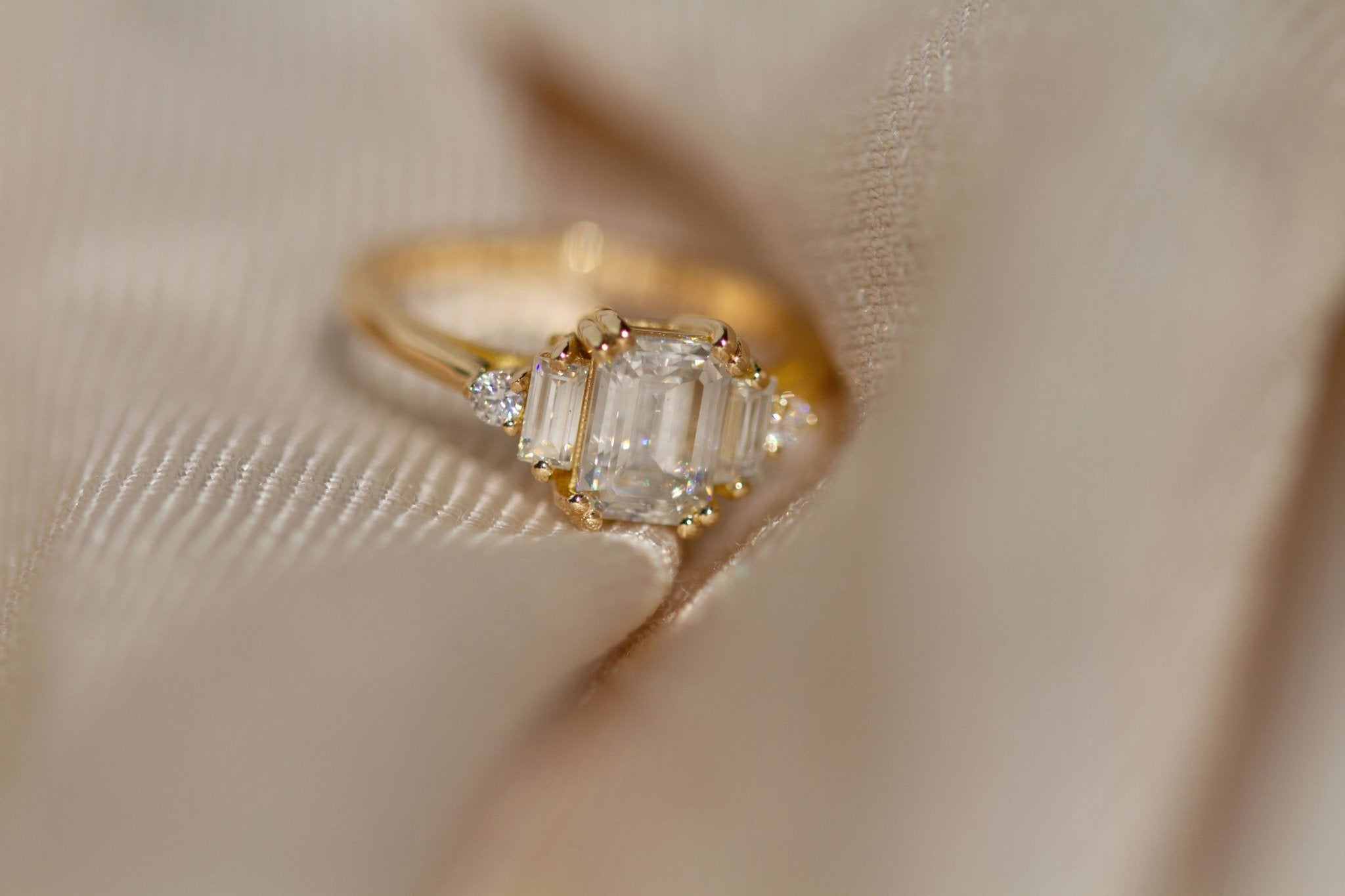 Rings-Product Details - Features an 7 x 5mm emerald cut Supernova Moissanite as the centre stone and baguette and round on the sides- Moissanite is a laboratory created gemstone that is very durable making it suitable for an engagement ring and everyday wear. Moissanite is not a lab grown diamond. The ring will come with a card of authenticity stating that it is featuring a Supernova Moissanite.- The ring is 1.80mm wide and thick-ELIISE MAAR JEWELLERY