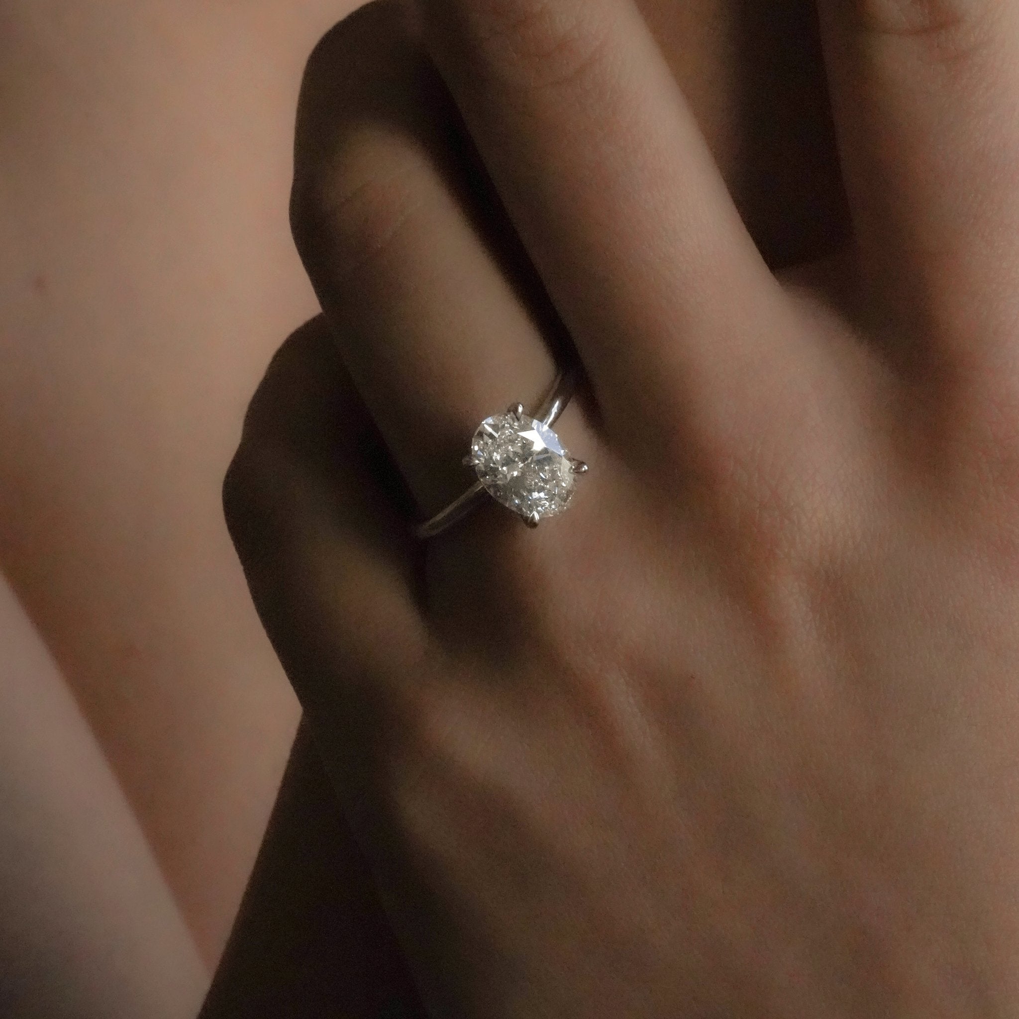 Rings-Drawing inspiration from Grace Kelly, this solitaire ring embodies timeless elegance. Featuring a 4-claw setting and a smoothly rounded band, it offers a subtle frame that highlights the radiant oval diamond at its center. An ideal engagement ring, it complements any wedding band to form a distinctive and personalized set. Shown paired with the 4.0mm Ceremonial Square Band and the Eleanor Luxe Diamond Band.-ELIISE MAAR JEWELLERY