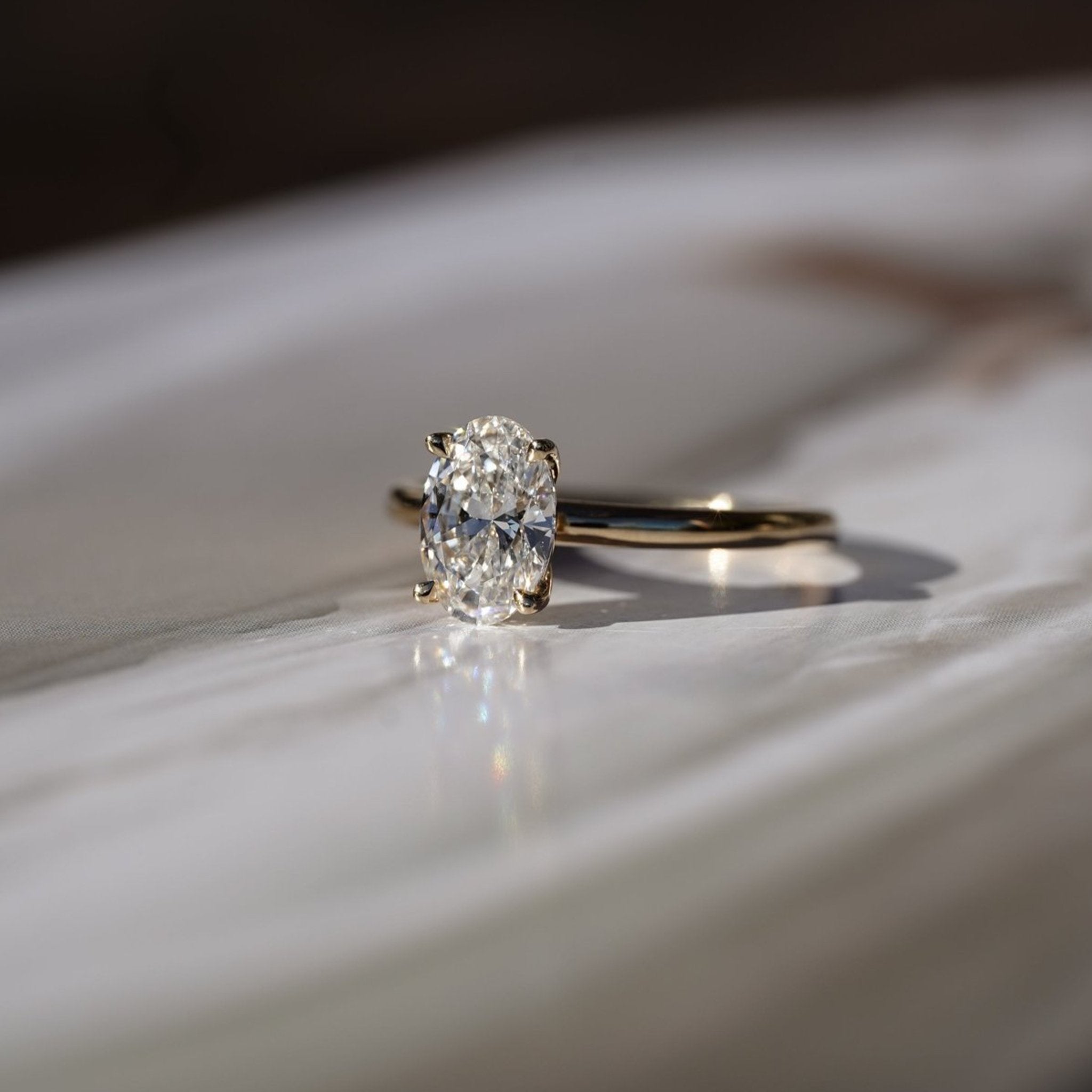 Rings-Drawing inspiration from Grace Kelly, this solitaire ring embodies timeless elegance. Featuring a 4-claw setting and a smoothly rounded band, it offers a subtle frame that highlights the radiant oval diamond at its center. An ideal engagement ring, it complements any wedding band to form a distinctive and personalized set. Shown paired with the 4.0mm Ceremonial Square Band and the Eleanor Luxe Diamond Band.-ELIISE MAAR JEWELLERY