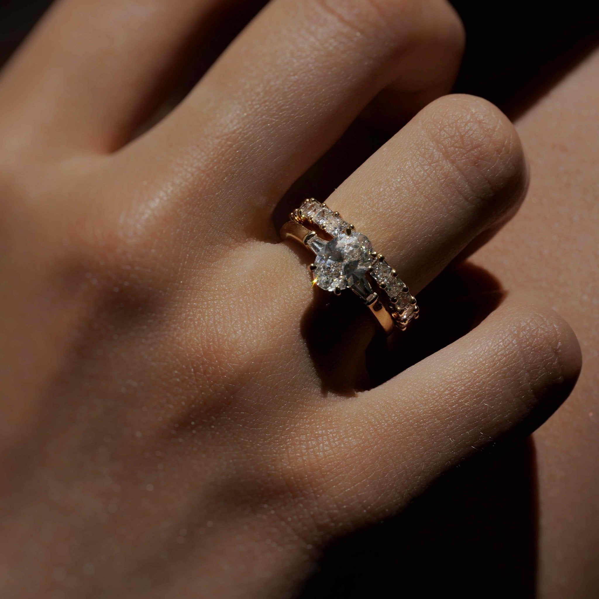 Rings-The Willow is a captivating engagement ring. The side tapered baguette cut stones create a beautiful crescendo to the centre oval cut diamond. The thicker band creates a ring that is structured and impactful. Shown paired with the Petite Nadia.-ELIISE MAAR JEWELLERY